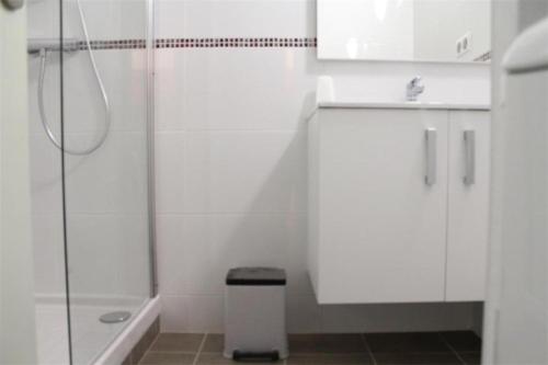 - une salle de bains blanche pourvue d'une douche et d'une poubelle dans l'établissement Appt 2 pièces cabine LA ROCHELLE - LR120-307, à La Rochelle