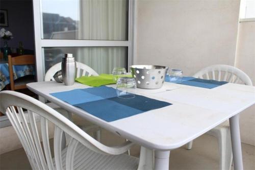 une table blanche avec des chaises blanches et un chiffon de table bleu dans l'établissement Appt 2 pièces cabine LA ROCHELLE - LR120-307, à La Rochelle