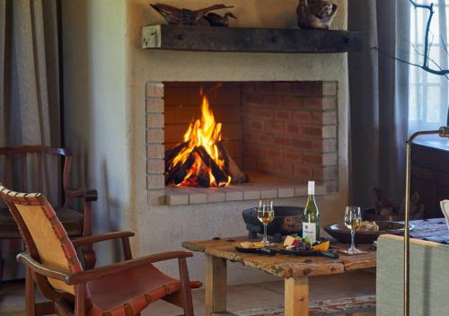 a living room with a fireplace with a table with wine glasses at Geiger's Camp in Timbavati Game Reserve by NEWMARK in Timbavati Game Reserve
