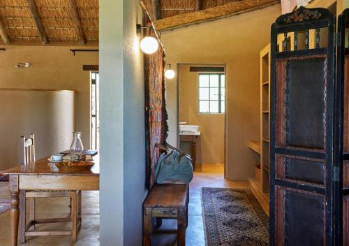 a room with a table and a wooden door at Geiger's Camp in Timbavati Game Reserve by NEWMARK in Timbavati Game Reserve