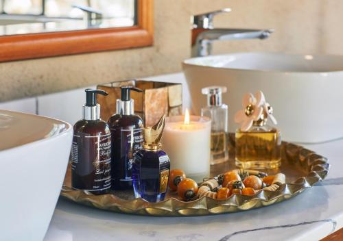 a tray with bottles of soap and candles on a bathroom counter at Geiger's Camp in Timbavati Game Reserve by NEWMARK in Timbavati Game Reserve