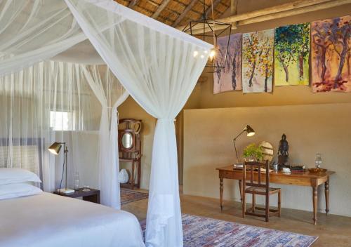 a bedroom with a bed and a table and a desk at Geiger's Camp in Timbavati Game Reserve by NEWMARK in Timbavati Game Reserve