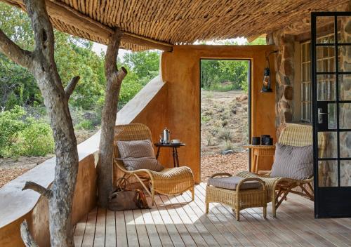a porch with chairs and a table and a tree at Geiger's Camp in Timbavati Game Reserve by NEWMARK in Timbavati Game Reserve