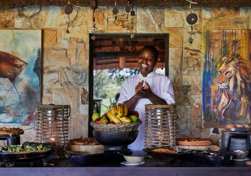 a man standing behind a counter with a bowl of fruit at Geiger's Camp in Timbavati Game Reserve by NEWMARK in Timbavati Game Reserve
