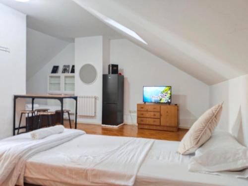 a white bedroom with a bed and a tv at habitación BARAJAS in Madrid