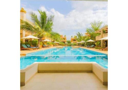 a swimming pool at a resort with palm trees at Villa Mandhari - Diani Beach in Diani Beach