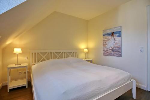 a bedroom with a white bed and two night stands at Villa Seepferdchen Wohnung 10 in Kühlungsborn