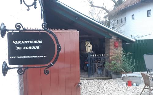 a sign in front of a red gate at Vakantiehuis de Schuur in Munstergeleen