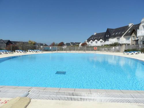 une grande piscine bleue avec des chaises et des maisons dans l'établissement Ref 028 Bel appartement RDC pour 4 personnes avec terrasse et piscine l'été, à Arzon