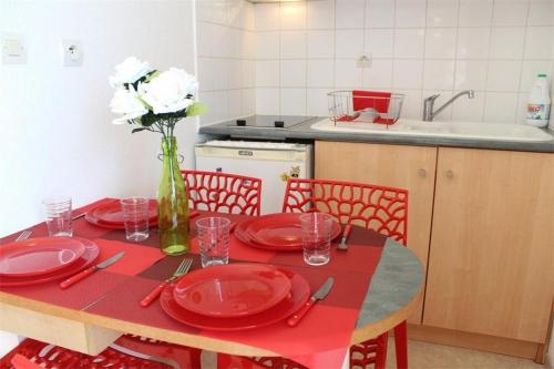 une table avec des plaques rouges et un vase avec des fleurs blanches dans l'établissement Appt 2 pièces LA ROCHELLE - LR030-E215, à La Rochelle