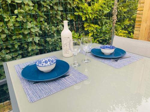 a table with blue plates and glasses and a bottle at Le studio de Marie in Noves