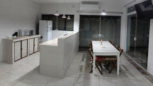 une cuisine avec une table et un comptoir blanc dans l'établissement Casa de Praia em Bertioga, São Paulocom Piscina Ar Condicionado Wifi a 500m do Mar, à Bertioga