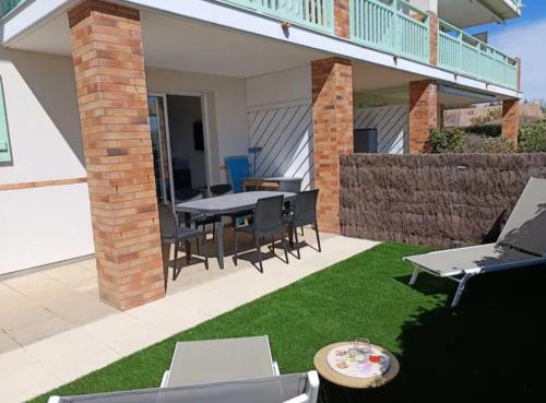 a patio with a table and chairs on the grass at T2 Parc du Golf in Pornic