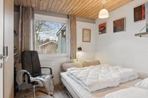 ein Schlafzimmer mit einem Bett und einem Stuhl und einem Fenster in der Unterkunft Feriehus 1102 in Ulfborg