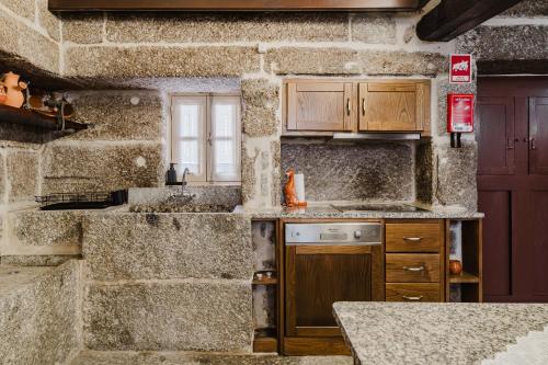 a kitchen with a stone wall with a sink and a counter at Cantinho da Tilde in Fafe