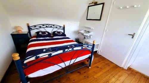 - une chambre avec un lit à rayures rouges blanches et bleues dans l'établissement Ar Véadès maison bretonne au grand calme, à Trébeurden