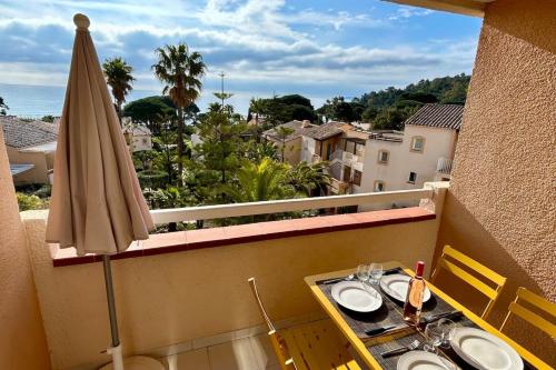 einen Balkon mit einem Tisch und einem Sonnenschirm in der Unterkunft L'Anse de Pramousquier T2 Vue Mer ! Bord de plage in Le Lavandou