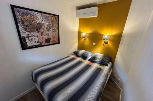 - un petit lit dans une chambre avec une photo sur le mur dans l'établissement L'Anse de Pramousquier T2 Vue Mer ! Bord de plage, au Lavandou