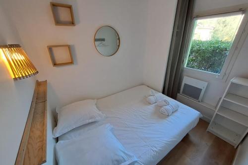ein weißes Bett in einem Zimmer mit Fenster in der Unterkunft F2 at "Domaine de la Pinède" Heated Swimming Pool in Le Lavandou