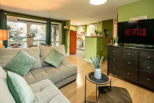 a living room with a couch and a television at Summer Deals up to 20 Percent OFF! Cosy Central London Family Stay Near Top Attractions - London Bridge & Shard - 3 Nearby Stations & Parking - WiFi & Games! in London