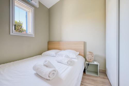 une chambre avec un lit blanc avec des serviettes dessus dans l'établissement Mazet NEUF - Résidence Tahiti Park piscine, au Lavandou