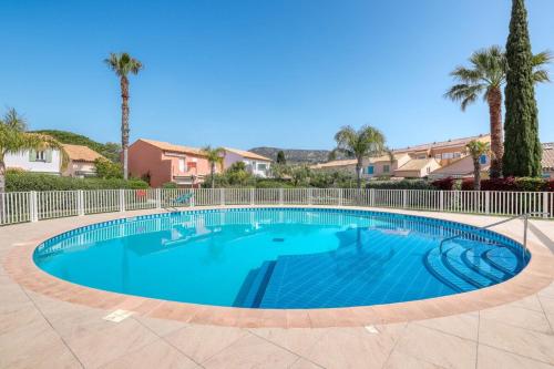 une grande piscine avec une clôture et des palmiers dans l'établissement Mazet NEUF - Résidence Tahiti Park piscine, au Lavandou