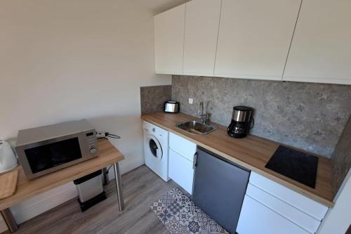 une cuisine avec des armoires blanches, un évier et un micro-ondes dans l'établissement Apartment 300 m from Saint-Clair beach, au Lavandou