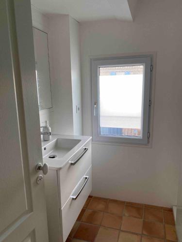une salle de bain blanche avec un lavabo et une fenêtre dans l'établissement Charmante maison à l'île de Ré au calme, avec jardin et deux vélos, à Saint-Clément-des-Baleines