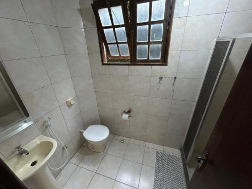 a bathroom with a toilet and a sink and a window at Pousada Recanto do Alto de Teresópolis in Teresópolis