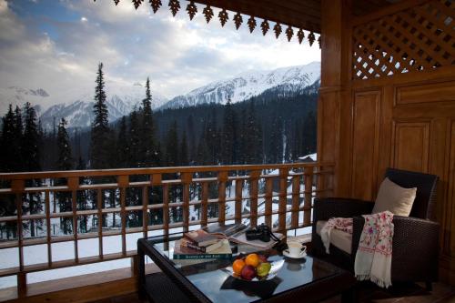 a balcony with a table and a view of a snowy mountain at The Khyber Himalayan Resort & Spa in Gulmarg