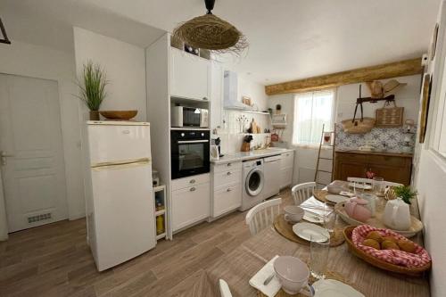 kuchnia ze stołem i białą lodówką w obiekcie Charming Air-Conditioned One-Bedroom 150m from Cavalière Beach w mieście Le Lavandou