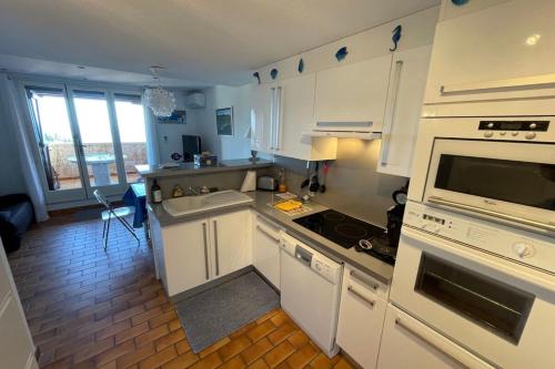 une cuisine avec des armoires blanches et un four à plaques de cuisson dans l'établissement Duplex in Pramousquier - sea view, au Lavandou