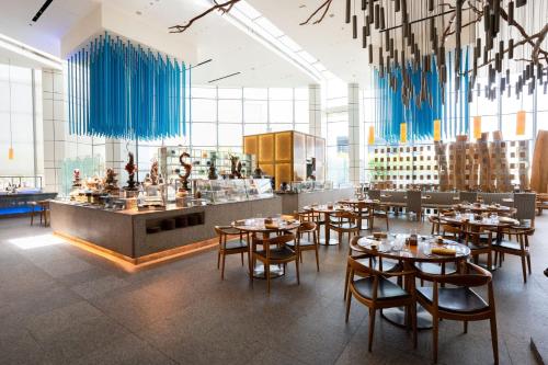 a restaurant with wooden tables and chairs and blue curtains at InterContinental Dubai Festival City by IHG in Dubai