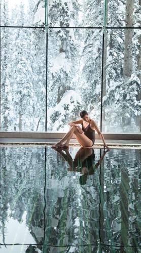 a woman sitting on the edge of a swimming pool at The Khyber Himalayan Resort & Spa in Gulmarg