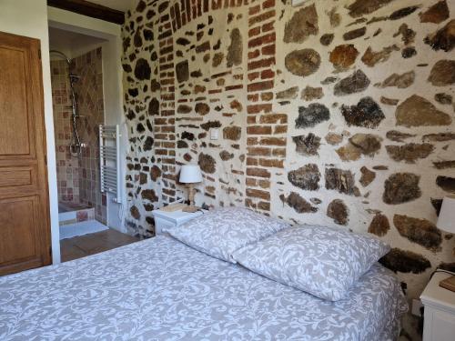 une chambre avec un mur en pierre avec un lit dans l'établissement Le Mas Joyeux - Le Lys - Gite En Cévennes, à Saint-Florent-sur-Auzonnet