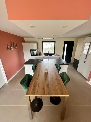 une cuisine avec une table en bois et des chaises vertes dans l'établissement Villa Coco 3 chambres, à Parentis-en-Born