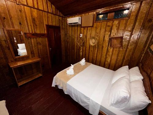 a bedroom with a white bed in a wooden wall at Vista do Lago Jungle Lodge in Cajual