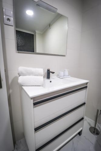 a white bathroom with a sink and a mirror at Apartamento Amanhecer in Rabo de Peixe