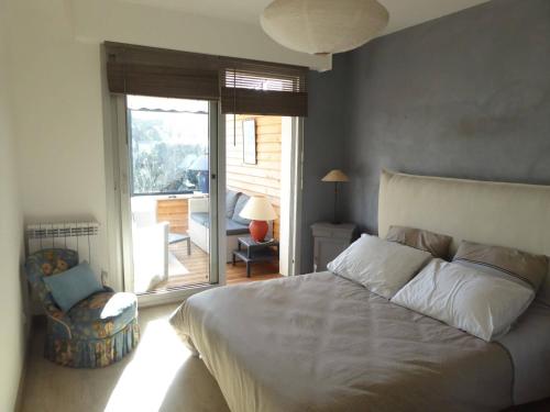 - une chambre avec un lit, une chaise et un balcon dans l'établissement REF 009 Maison 3 chambres avec jardin proche commerces et bourg d'Arzon, à Arzon
