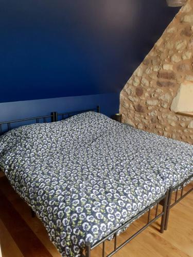 a bed in a room with a stone wall at La petite maison du Ramail in Badefols-dʼAns