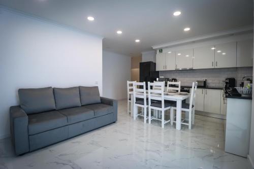 a living room with a couch and a table and a kitchen at Apartamento Amanhecer in Rabo de Peixe