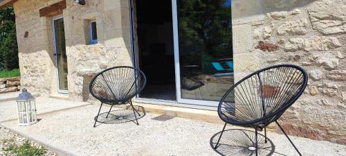 two black chairs sitting in front of a building at La petite maison du Ramail in Badefols-dʼAns
