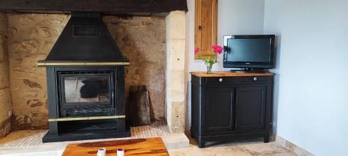 a living room with a television and a fireplace at La petite maison du Ramail in Badefols-dʼAns