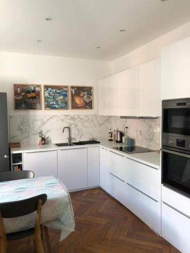 une cuisine avec des armoires blanches, une table et un évier dans l'établissement La Residence, Beautiful Comfort, à Saint-Gervais-les-Bains