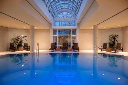 a swimming pool with chairs and a table in a building at Leonardo Hotel Weimar in Weimar