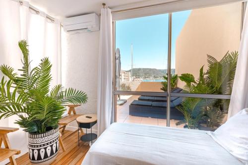 a bedroom with a bed and a balcony with plants at Superb apartment on the port of Favière in Bormes-les-Mimosas