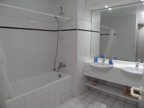 a white bathroom with a tub and a sink and a bath tubermott at REF 024 Appartement deux chambres vue mer parc du Fogeo Arzon in Arzon