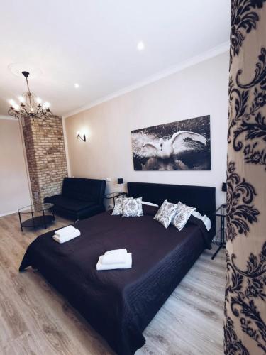 a bedroom with a black bed and a couch at Apartments Vitenberg in Cēsis
