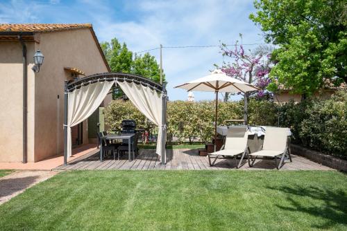 a patio with a table and chairs and an umbrella at Podere Vignanova Accommodations & SPA in Castagneto Carducci