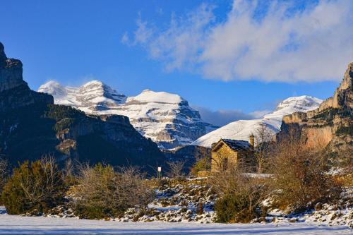 a snow covered mountain range with a house in the foreground at As Fuebas de Patricio in Vío